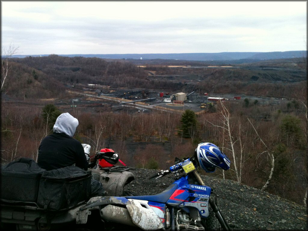 Yamaha dirt bike parked next to Yamaha Grizzly ATV carrying small gasoline can and extra cargo bags.