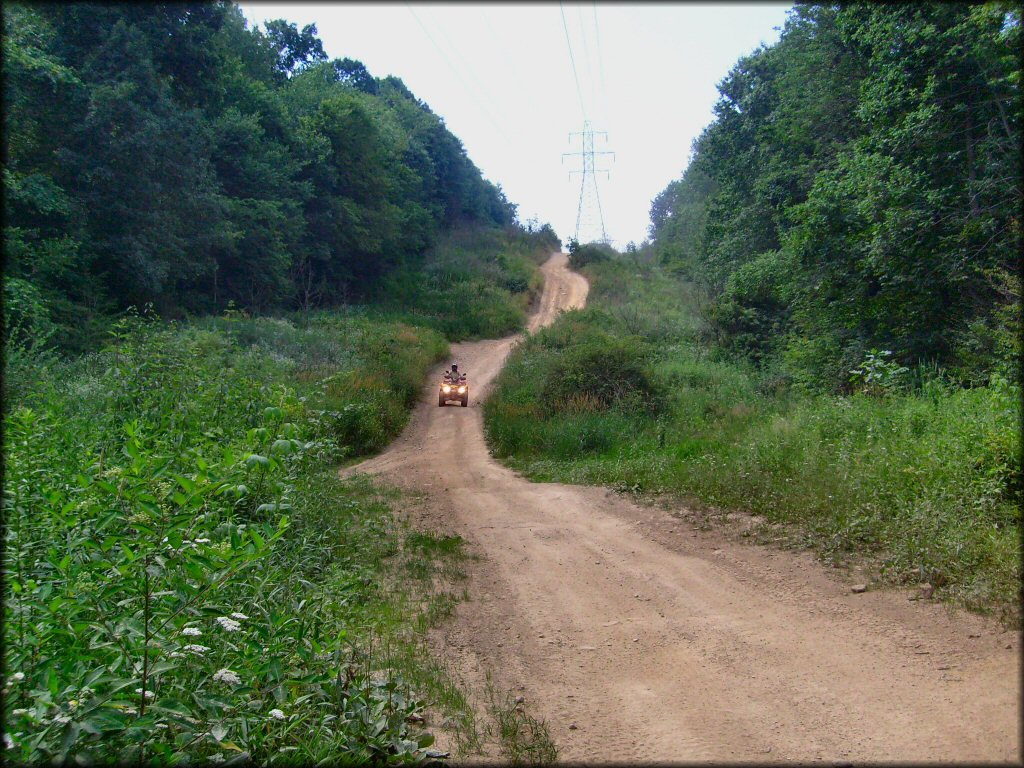 ATV on trail riding underneath powerlines.