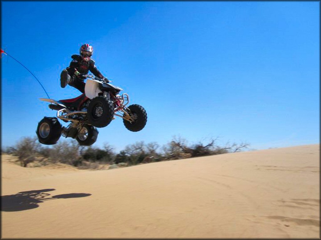 Rider catching some air on ATV with paddle tires.
