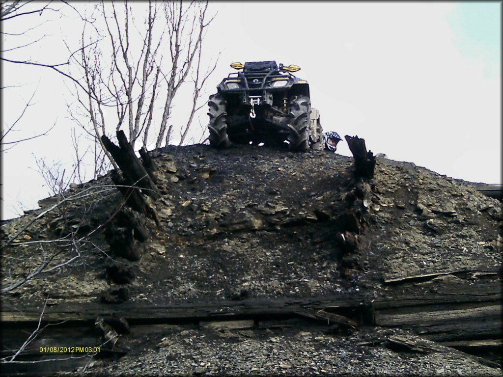 ATV with winch on the front bumper parked on top of dirt mound.