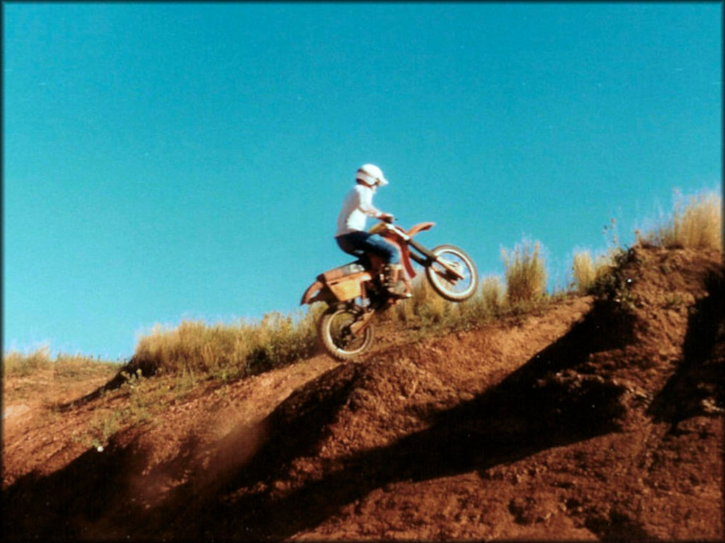 Dirt bike rider on a Suzuki RM 250 tackles a steep hill.