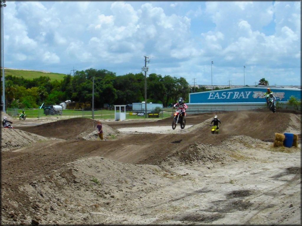 Honda, Suzuki and Kawasaki dirt bikes in the air on motocross track.