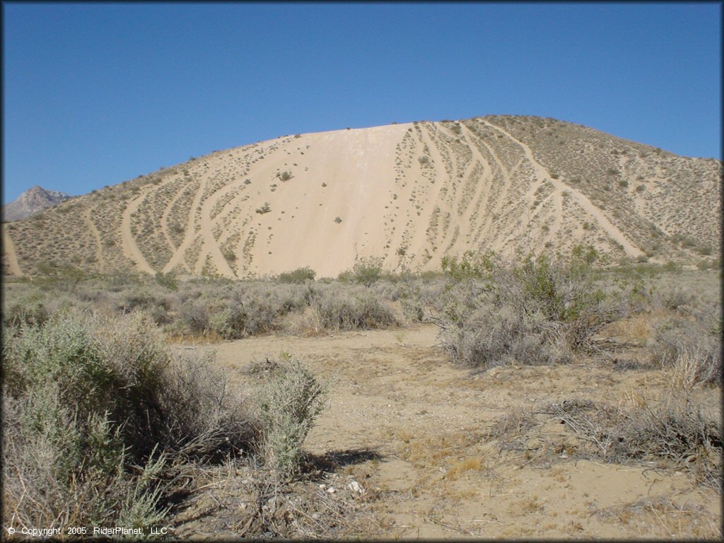 A photo taken far away of a steep and sandy hill climb.