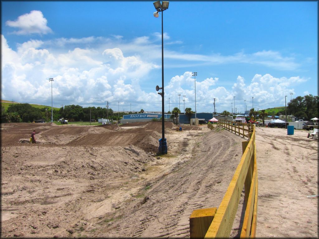 Motocross track with lights and surrounded by wooden fencing.