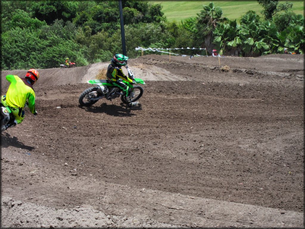 Three dirt bikes on track going through a turn.