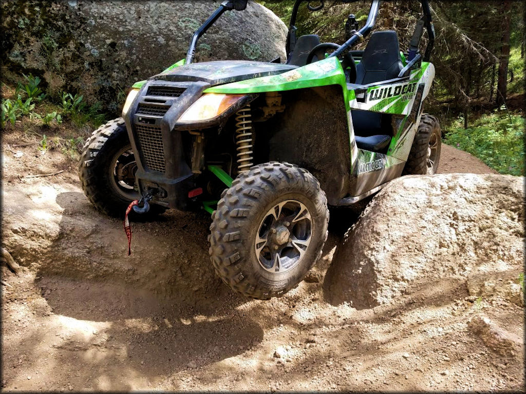 Arctic Cat Wildcat Sport UTV with front tow hitch parked on the trail between two large rocks.
