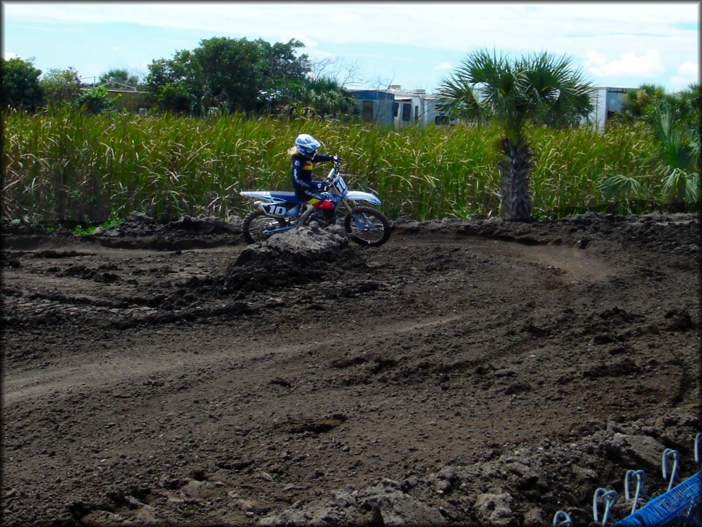 Woman on blue Yamaha dirt bike going through turn on motocross track.