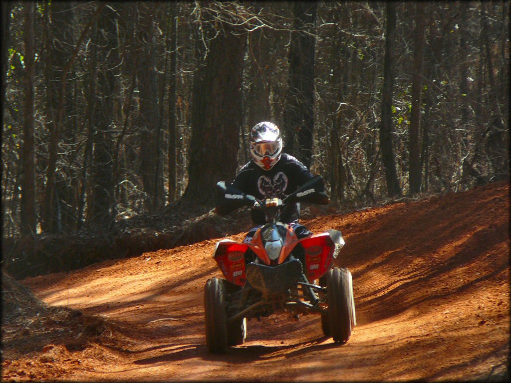 Honda four wheeler with MSR bark busters and UNI air filter decals navigating smooth ATV trail.