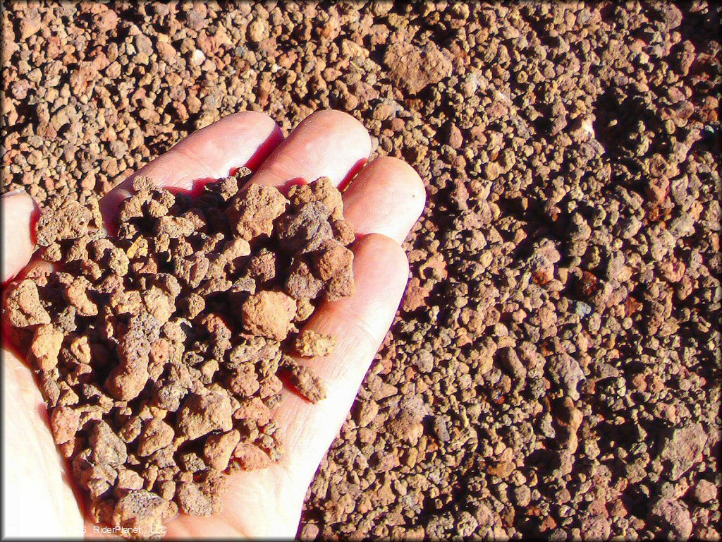 Close up photo of hand holding some tiny lava pebbles.