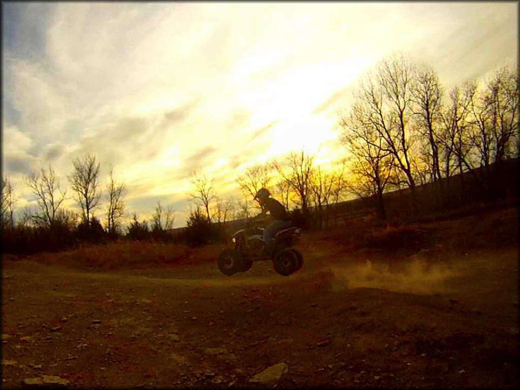 Man on ATV getting a little air from a small jump.