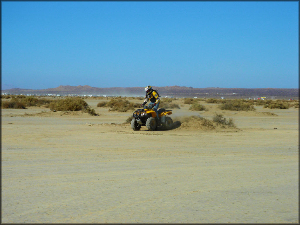 Man on Honda 250 ATV riding on flat terrain.