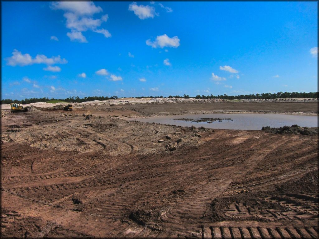 Heavy duty construction equipment next to large mud pit.