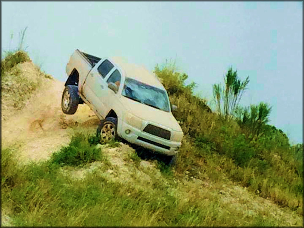 A 4x4 truck traverses down a very steep hill.