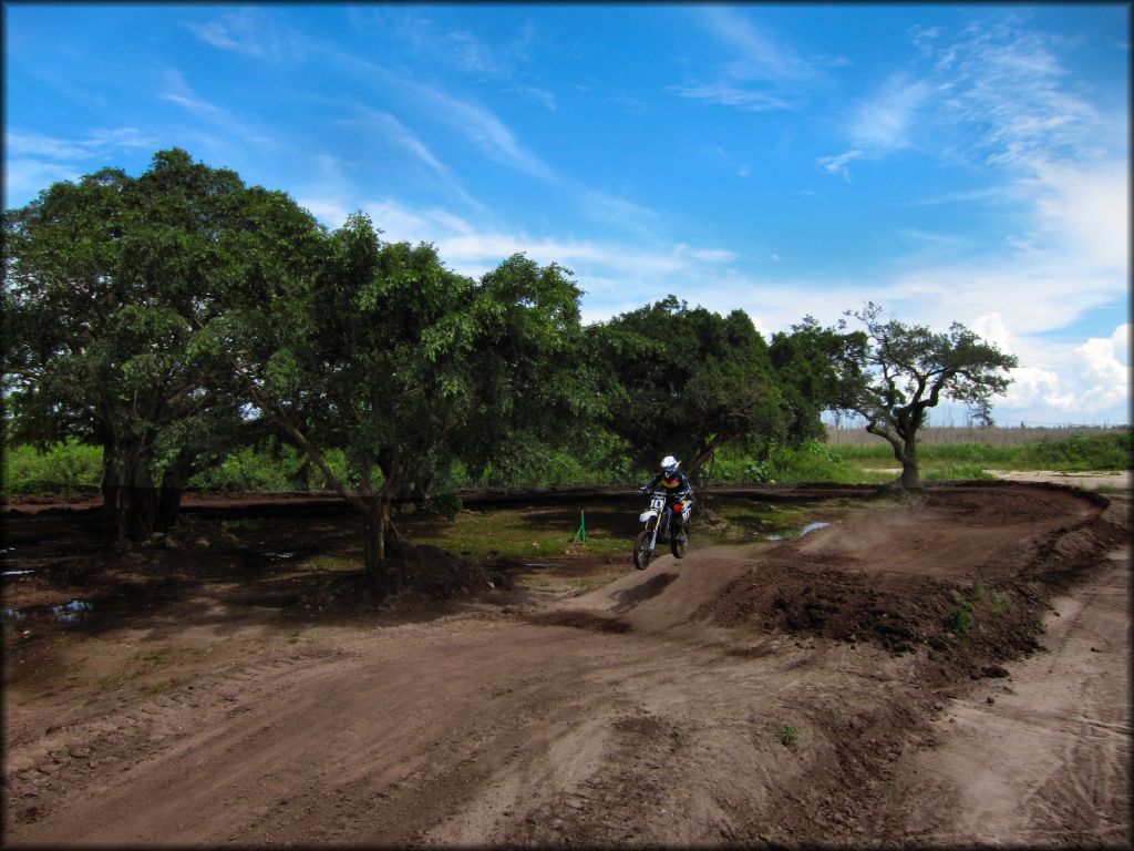 Woman on Yamaha motocross bike catching some air on track.