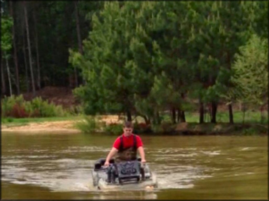 Teenage boy on black four wheeler going though deep water crossing.