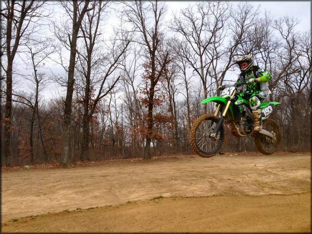 Kawasaki dirt bike catching some air on the motocross track.