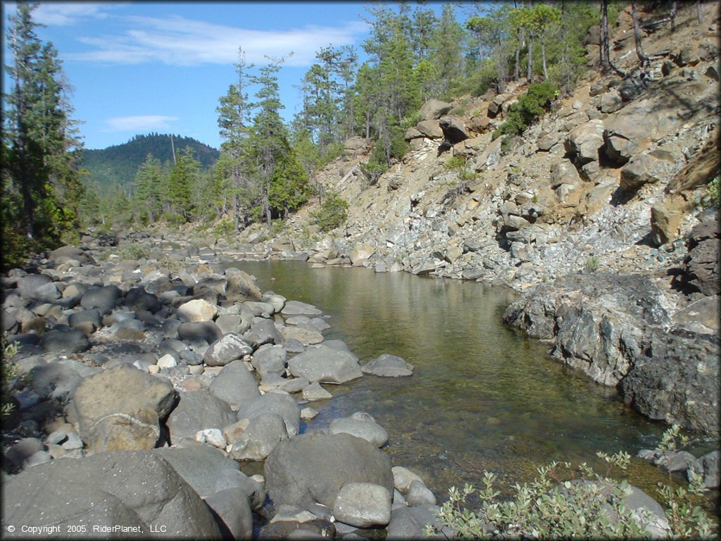 Close up photo of shallow stream surrounded by large river rocks.