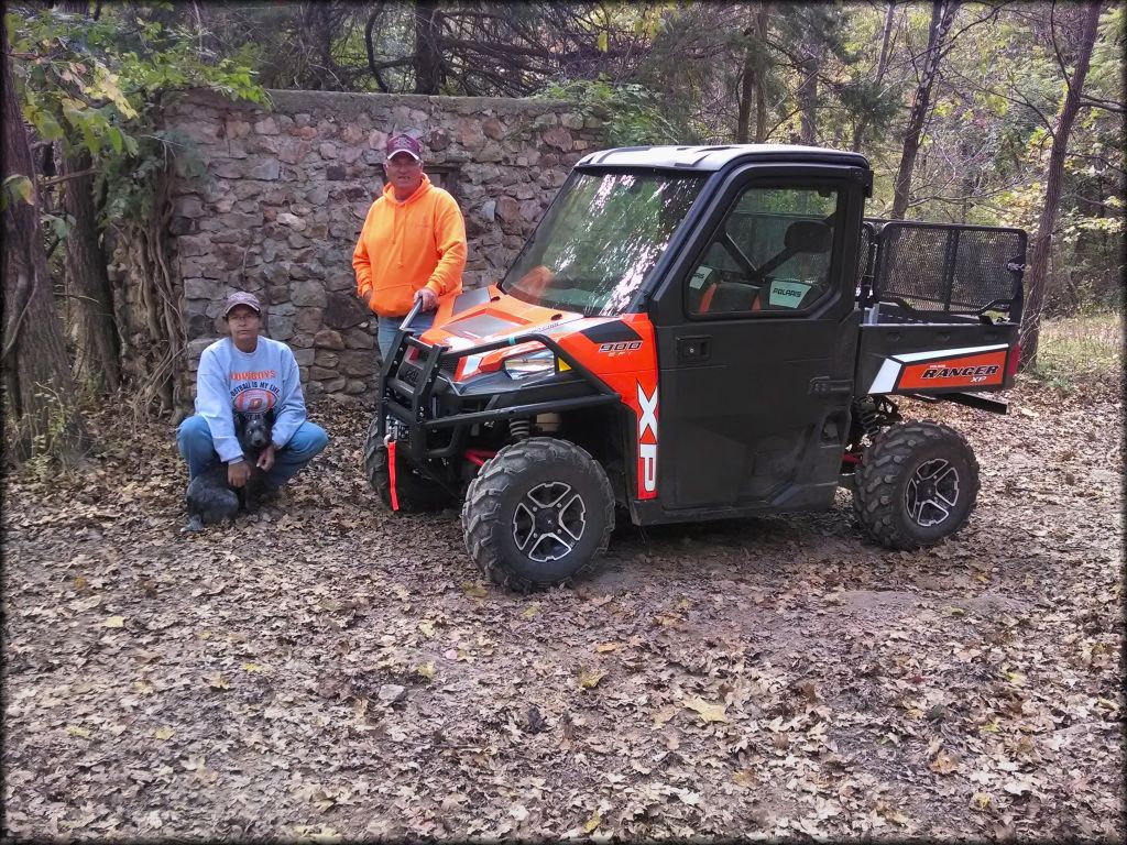 Polaris Ranger XP 900 with winch on the front bumper parked with man, woman and small dog nearby.