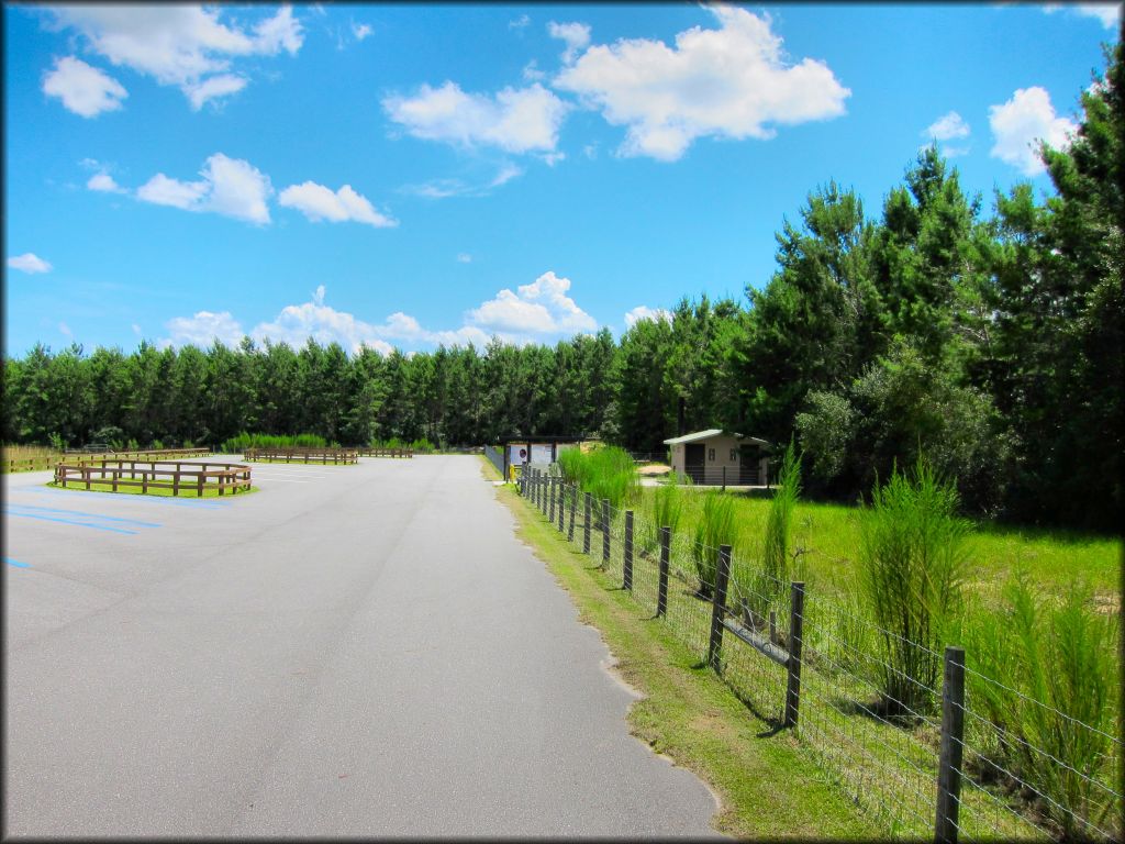 Photo of paved parking lot for OHVs with informational kiosks and vault toilets.