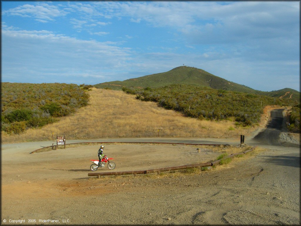 Man on Honda CRF250X riding near day use area for OHV parking.