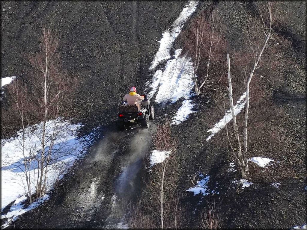 ATV carrying camouflage cargo bag in the rear climbing steep gravel and coal hill.