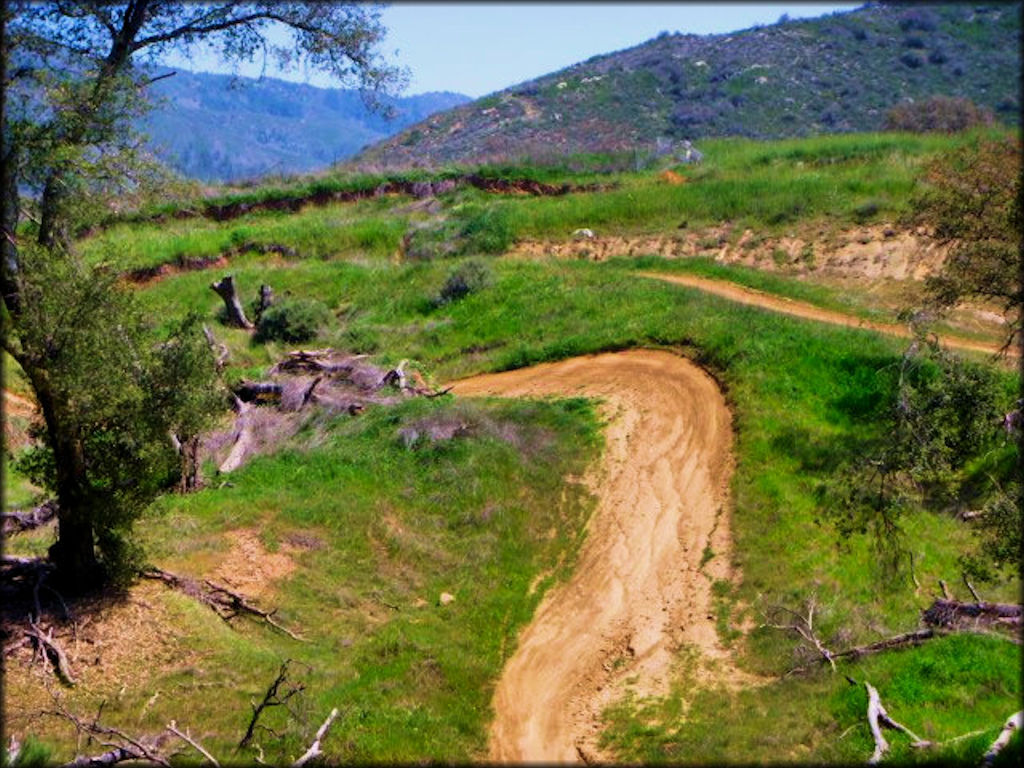 View of a motocross track with some rugged and hard packed sections.