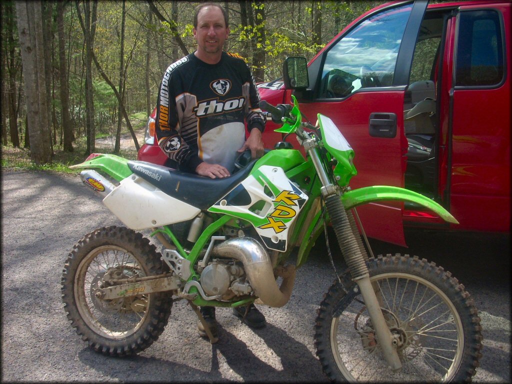 Man wearing Thor motocross jersey standing behind Kawasaki KDX two-stroke with FMF Fatty Pipe.