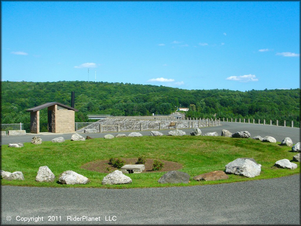 Photo of paved loop with vault toilet and park bench.