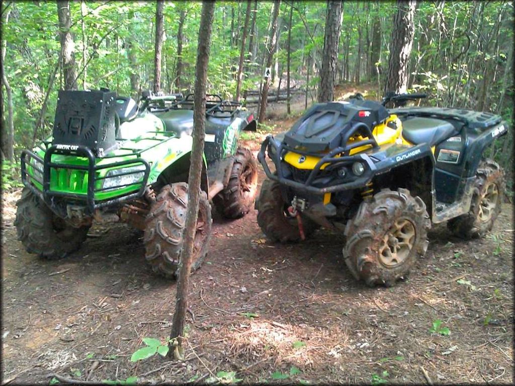 Can-Am Outlander and Arctic Cat ATV with mud tires parked on trail.