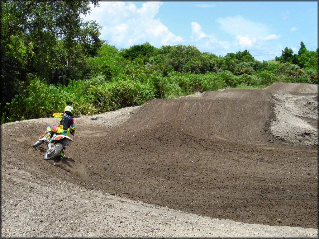 Young man riding through berm on motocross track.