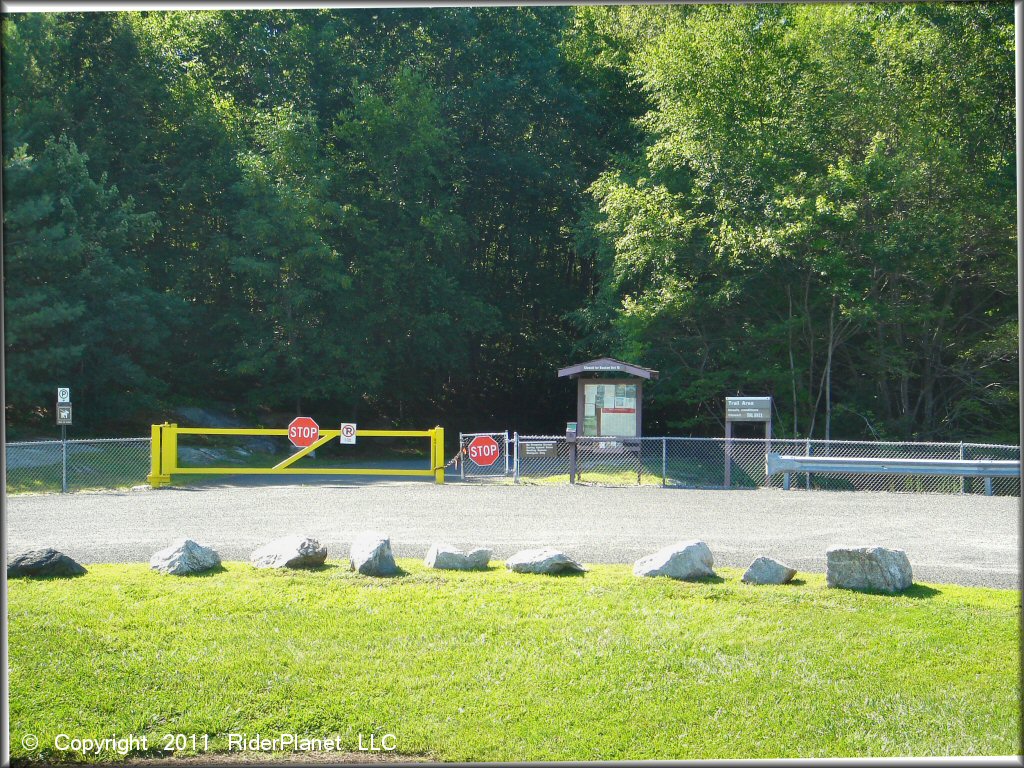 Gated yellow entrance with stop signs, chain link fence, singnage and information kiosk.