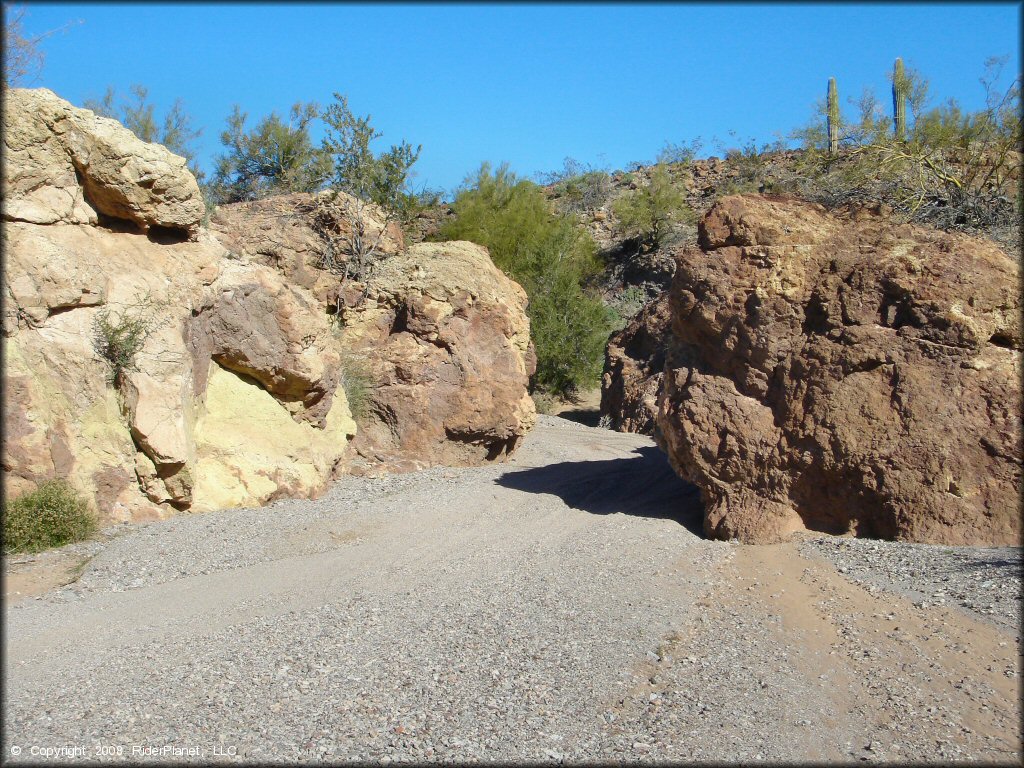A close up photo of sandy wash surrounded by large rock boulders.