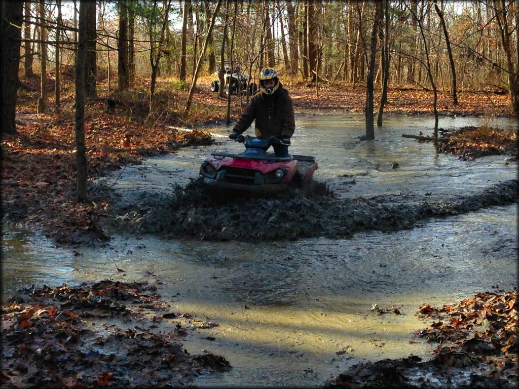 Four wheeler going through deep mud pit.